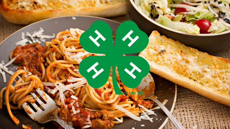 4-H clover in front of spaghetti, garlic bread, and salad