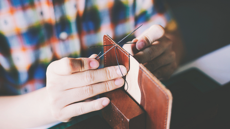 A person sewing a leather wallet.