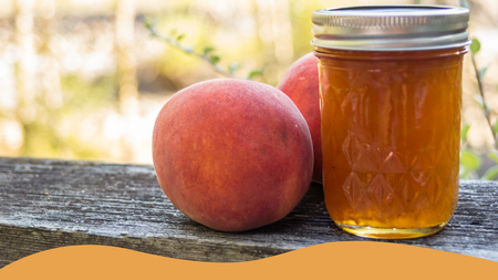 Peach jam in a jar with peaches sitting next to the jar sitting on a wooden banister.