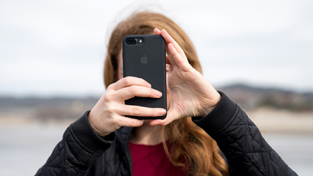 person with long red hair holding up a cell phone in front of face