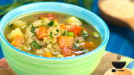 Vegetarian quinoa soup with carrot, potato, leek and tomato, sprinkled with parsley and scallion in colorful bowl.