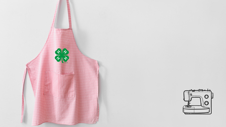 A pink apron with a green 4-H clover hanging on a hook. Graphic of a sewing machine in bottom right hand corner.