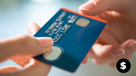 A person's hand passing their credit card over to another person's hand. 