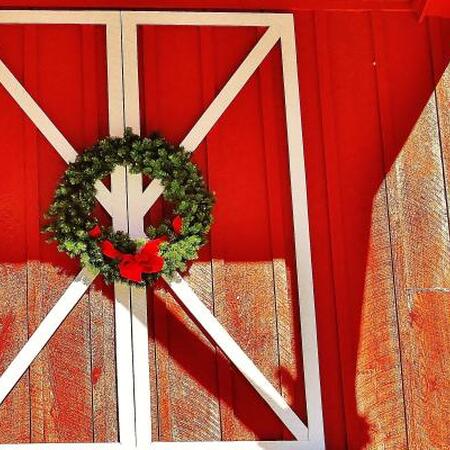 A holiday wreath hangs on red barn doors