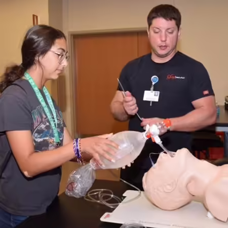 Instructor showing student how to intubate a training mannequin