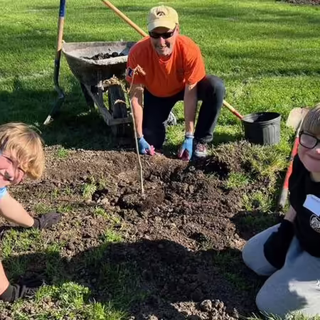 Kids and an adult planting trees