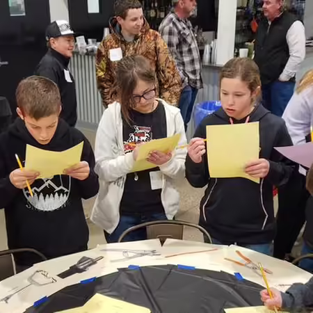 Kids standing around a table, each reading a piece of paper