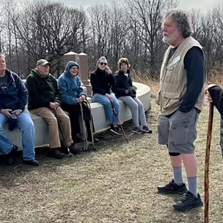 Group of people outdoors, listening to two people standing and talking