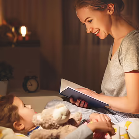 Parent reading a bedtime story to child in bed.