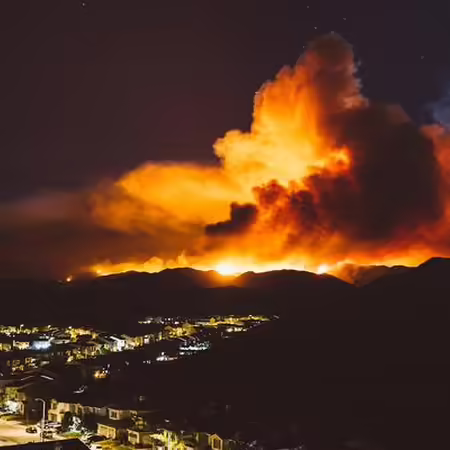 a fire burns at night in California just outside a city