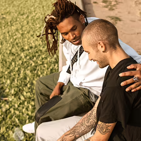 two men sitting on bench consoling each other for positive mental health