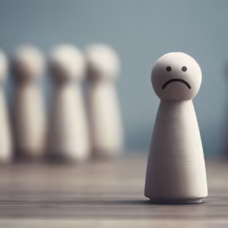 Wooden person with a frown stands in front of a group of wooden people.