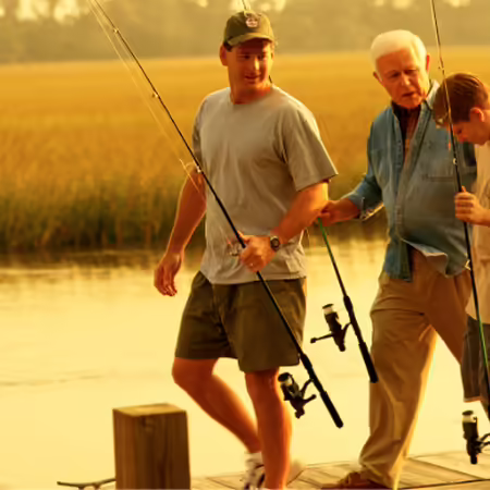 family of three males walking on a dog with fishing poles