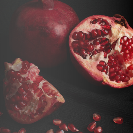 Pomegranate split open, with a few seeds on the table