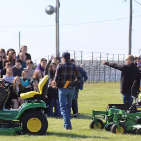 Group of youth sitting outside answering a question pertaining lawn mower safety. 