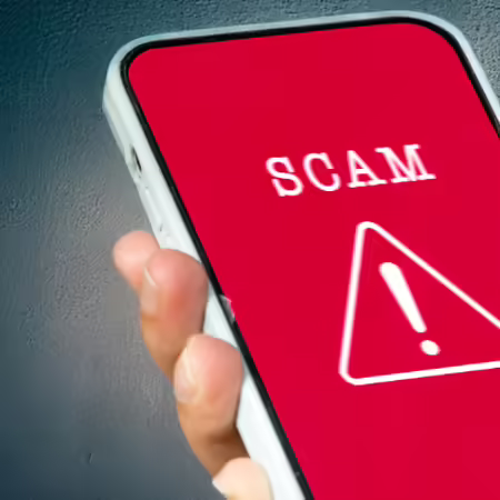The image shows a phone with the word scam on the screen.