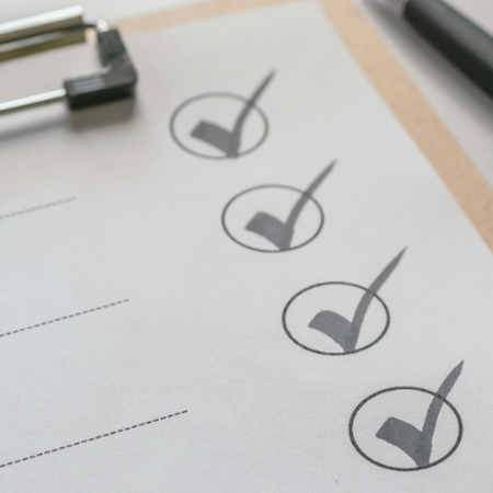 A blank checklist on a clipboard next to a pen.