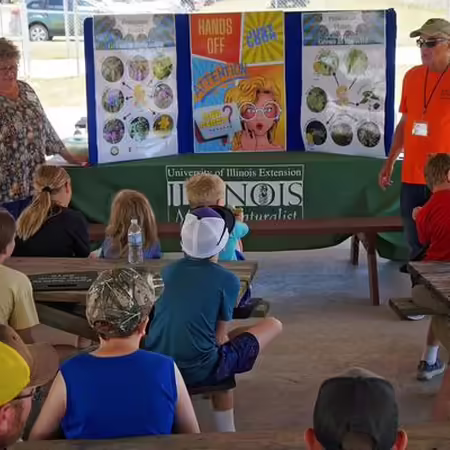 youth sitting on floor while adults present educational material