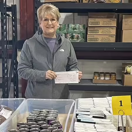 lady standing in front of a table full of food pantry donations