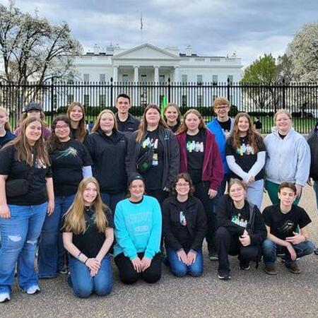 A group of teens pose on the street in front of the White House