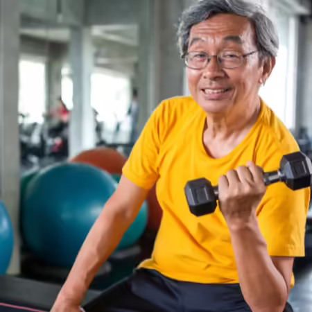 A middle-aged man performs a seated bicep curl strengthening exercise