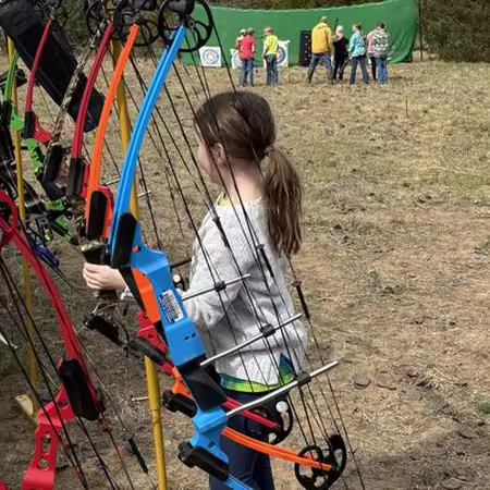 Child holding a bow at an archery range
