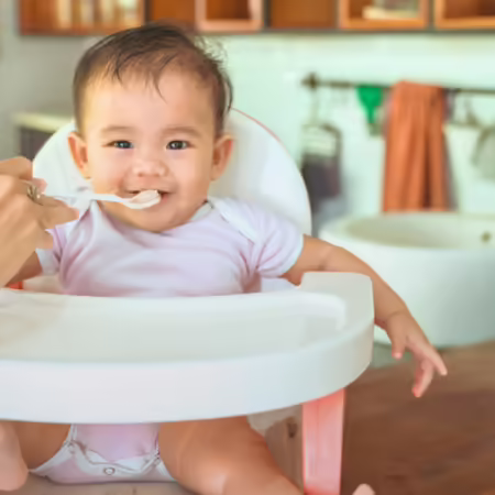 Baby in a high chair being fed