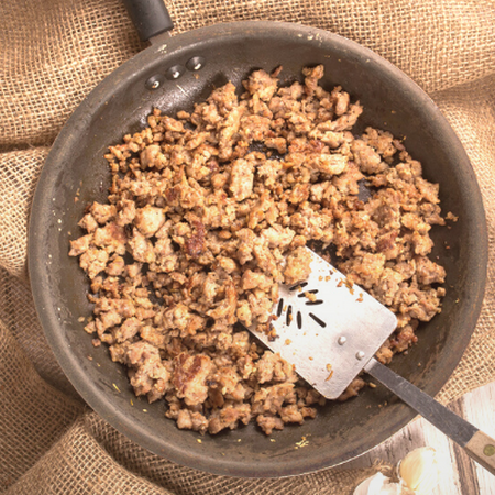 Image of a pan with ground meat and a spatula on burlap fabric