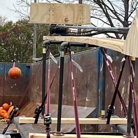 orange pumpkin being launched into a dumpster