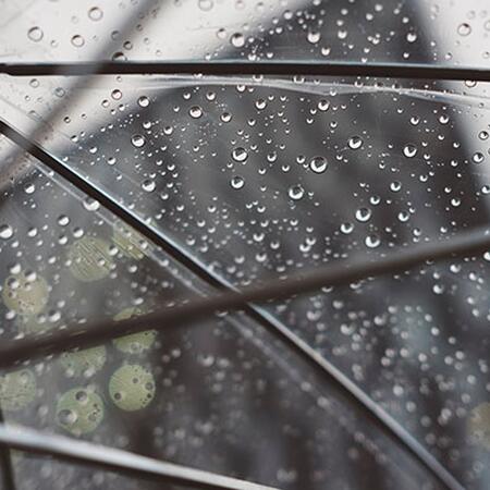 Raindrops hitting top of clear umbrella