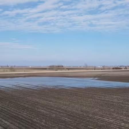 An agricultural empty field with water standing in low areas