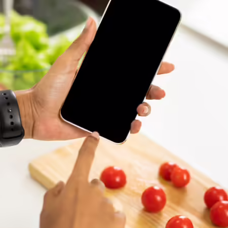 An image of a person's hands using a phone while preparing food