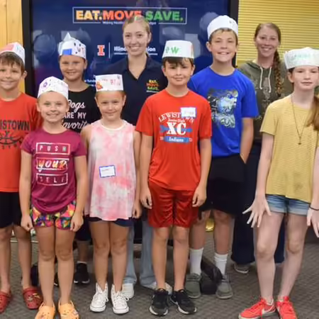 Kids taking a group photo with cooking hats on and some with aprons on