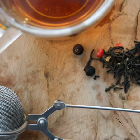 Cup of prepared tea on wood background with dry tea leaves and ball tea strainer. Photo by Melanie Dijkstra on Unsplash
