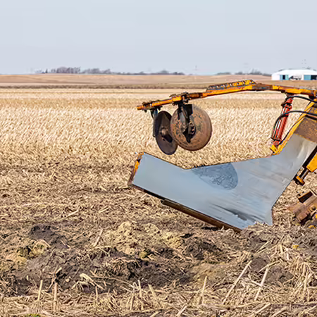 A tile plow attached to a tractor.