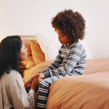 mother talking to child with child sitting on bed