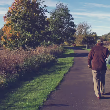 two people walking on a paved path in a park