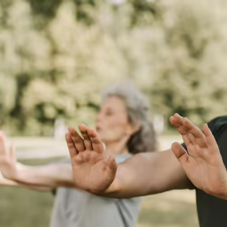 two people standing outside with hands facing palms out