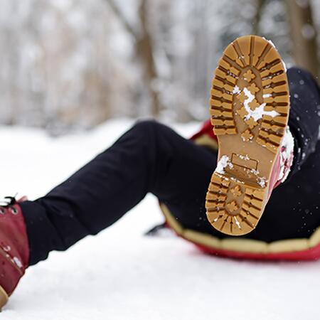 Shot of person during falling in snowy winter park. Woman slip on the icy path, fell and lies. Danger of season trauma.