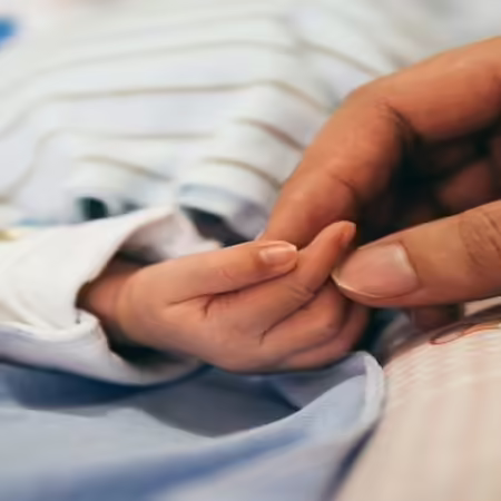 adult hand holding baby hand