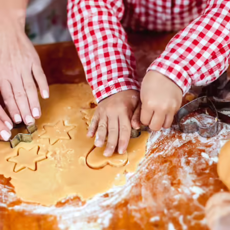 adult and child using cookie cutters with dough
