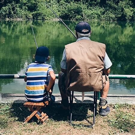 Man and boy fishing together at pond