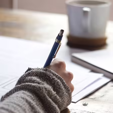 person writing on paper with pen