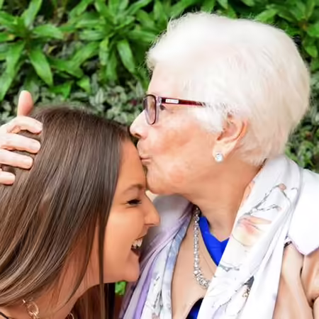 woman kissing forehead of older grandaughter