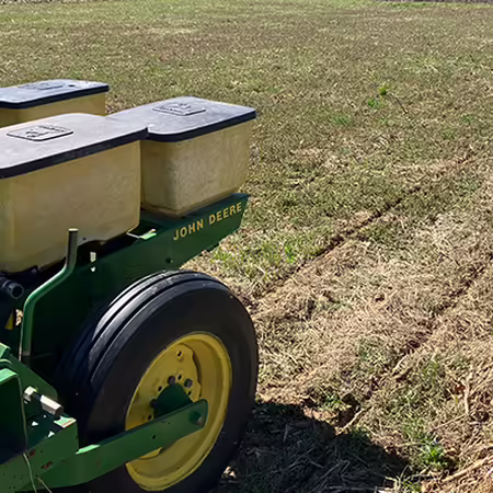 equipment on back of tractor drilling seeds into a field
