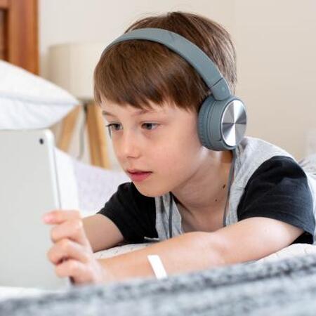 child with headphones on watching a tablet