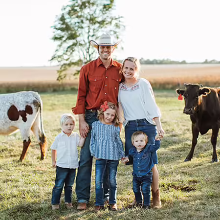 Sawyer stands with his wife, three kids, and cows