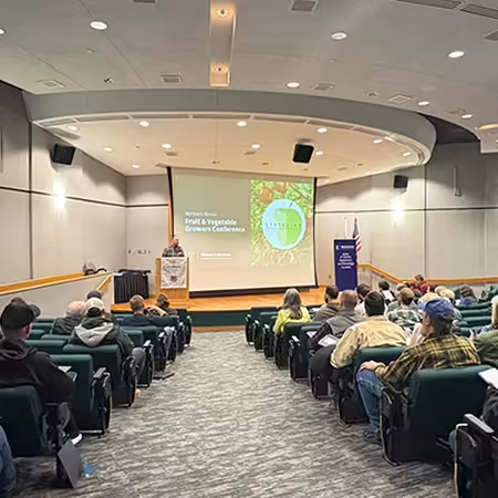 A group of people sitting in chairs in an auditorium at a college