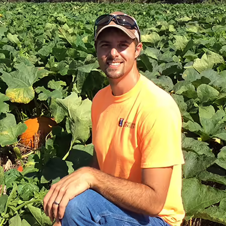 person kneeling in a pumpkin field