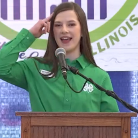 girl holding hand to head reciting 4-H pledge